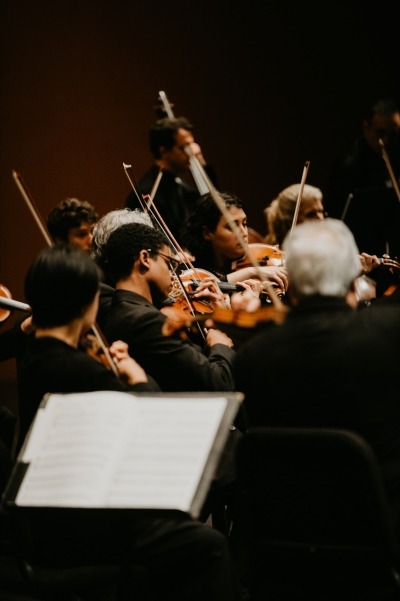 Image of the Orpheus Chamber Orchestra performing at the Lied Center with a music stand in the foreground and the string section in the background.