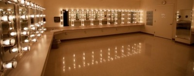 Image of a dressing room at the Lied Center with the makeup lights on surrounding mirrors and reflecting off of the tile floor