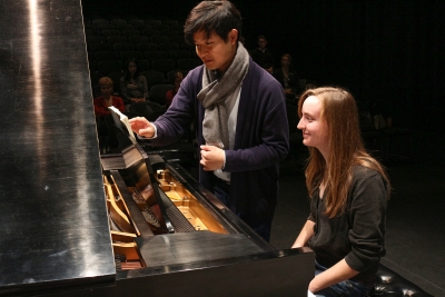 Image of Yekwon Sunwoo standing by a piano and pointing to the sheet music in front of a UNL student seated at the piano during a master class.