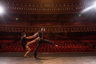 Image of two dancers dressed in black on the Lied Center stage looking out toward an empty auditorium