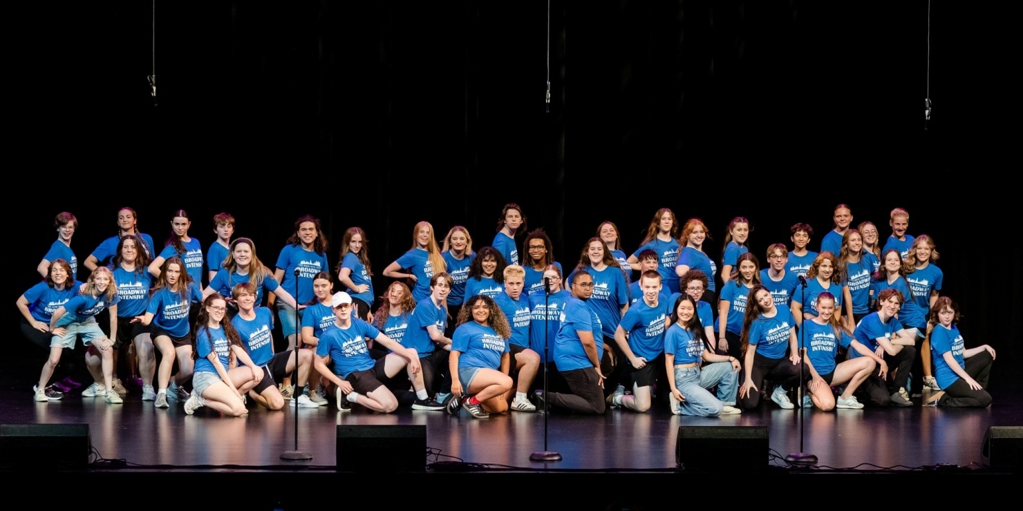 a large group of people in blue shirts pose together on stage