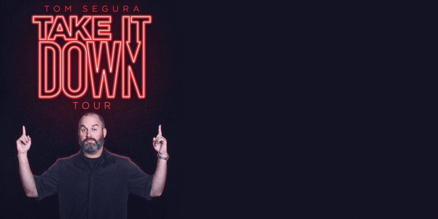 Tom Segura in a black T-shirt in pointing up to the words "TOM SEGURA TAKE IT DOWN TOUR" in red neon in front of a black background.