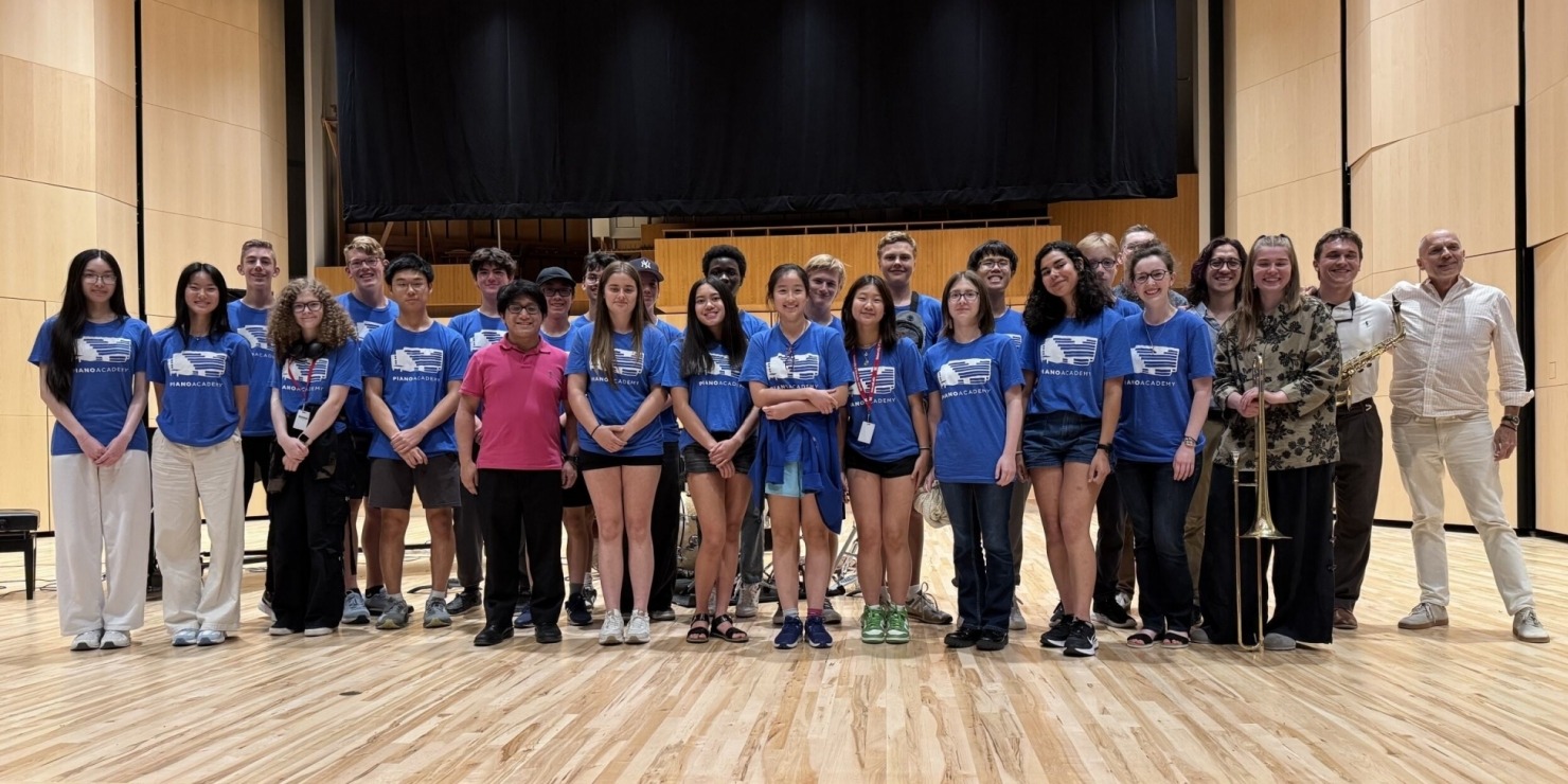 a group of students in matching blue shirts pose together on a stage