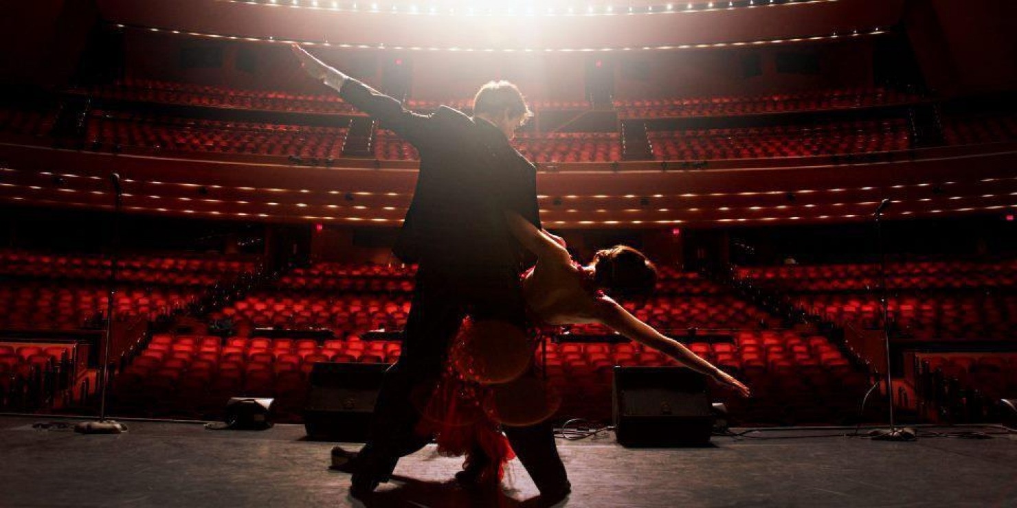 Man and woman doing an elegant dip on stage with their backs to the camera