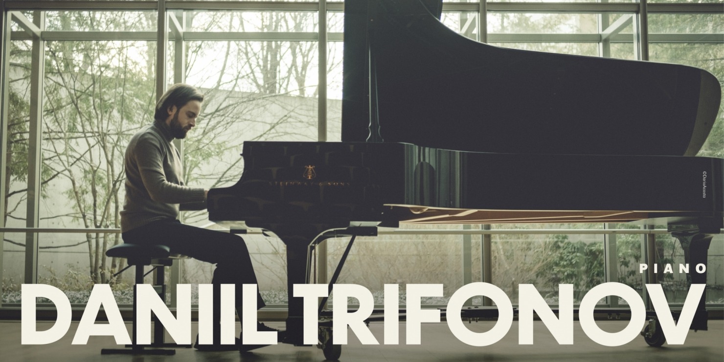 a man sits at a piano in a room with windows for walls