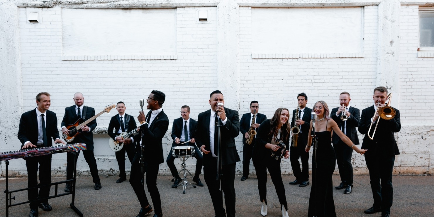 a group of humans dressed in black suits and dresses perform together with their instruments