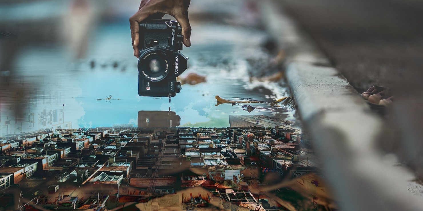 An image of a black camera photoshopped above a town.