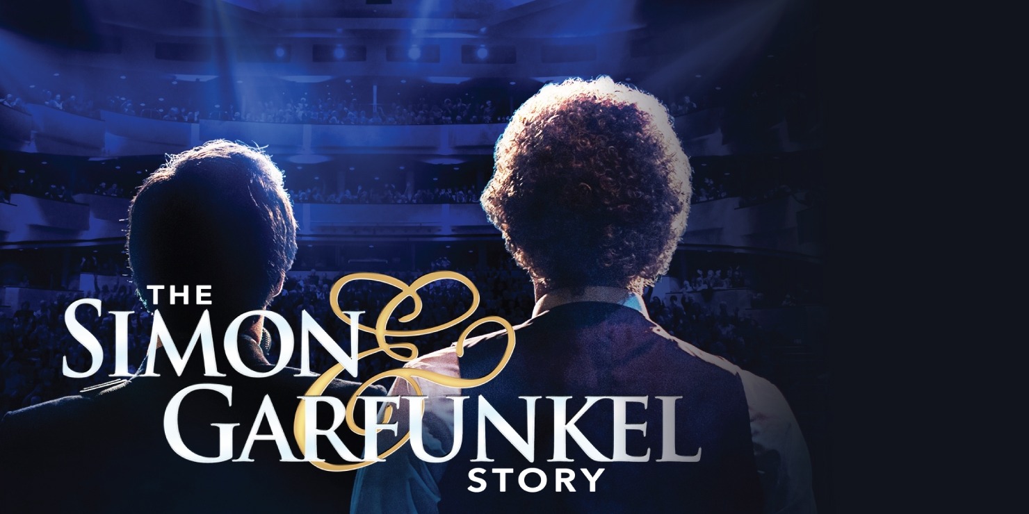 Two men facing away from the camera on a stage with blue lights shining onto the stage. Text at the bottom of the stage reads "The Simon & Garfunkel Story"