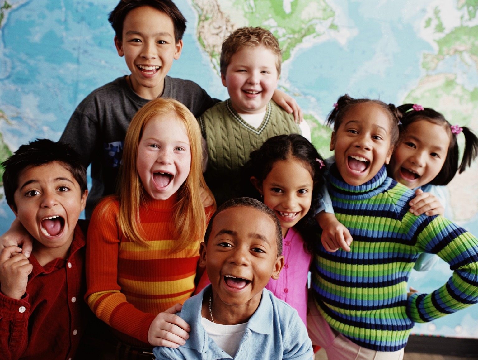 Image of six children standing close together and smiling widely at the camera