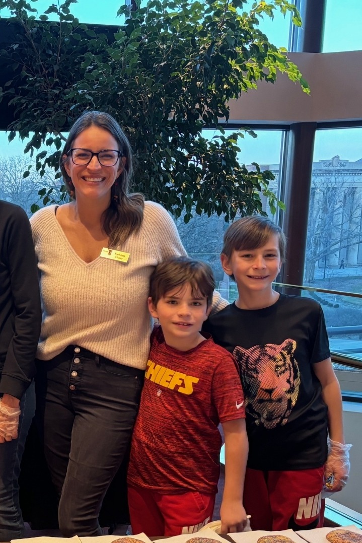 Image of a woman and two children volunteering in front of a table. 