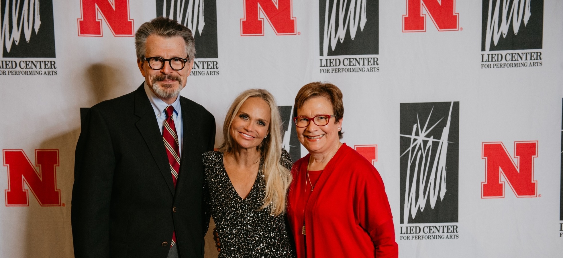 Photo of Kristin Chenoweth wearing a silver dress taking a meet and greet photo.