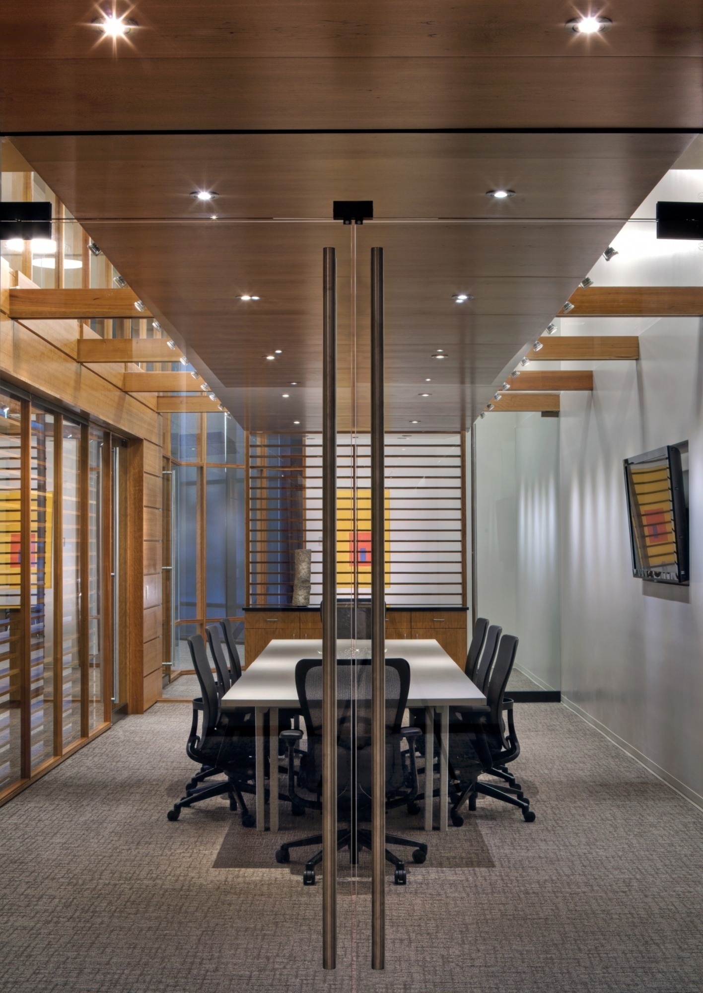 Image of the Lied Commons Boardroom taken through the glass doors showing the long table and a TV on the wall.