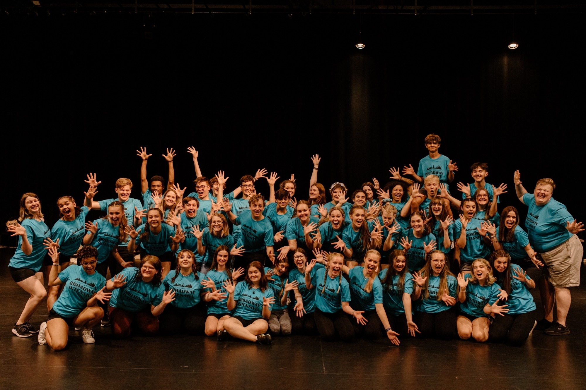 Young artists with blue shirts standing on stage in a group.