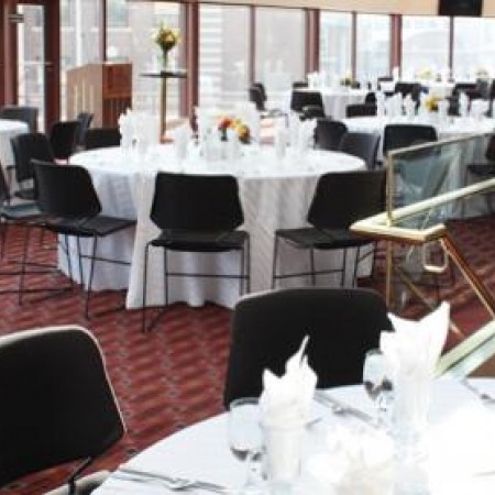 Image of the Lied Center Katherine Hendy Parker Lobby highlighting the beautiful view of the UNL campus and a banquet setup featuring black chairs around white tables.